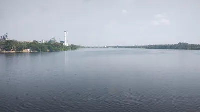 A calm wide river with a long bridge and a town on the far side