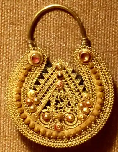 A gold pendant covered in fine granules and set with small stones