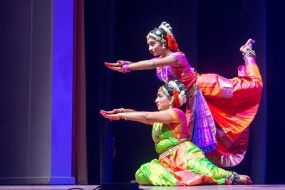 Two dancers in bright silk costumes striking a pose on a lit stage