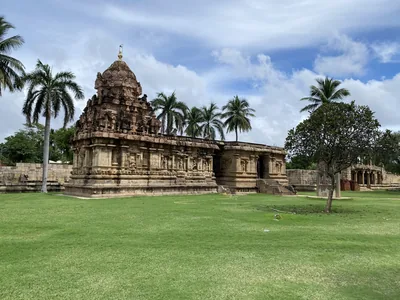 A smaller stone shrine on a green lawn with palm trees