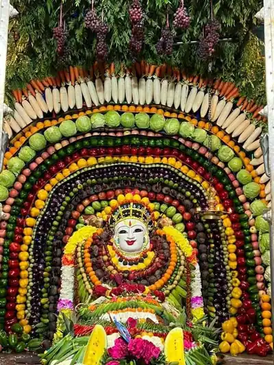 A shrine framed by rows of carrots, cabbages, grapes and gourds around a rice-covered deity