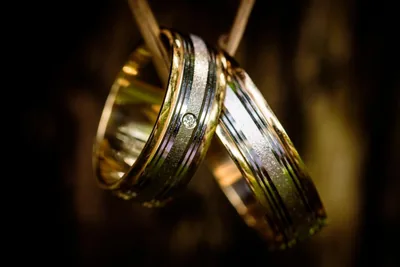 Two gold wedding rings hanging in warm light