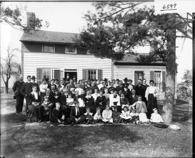 Many guests gathered on the lawn in front of a wooden house for a golden wedding in 1905