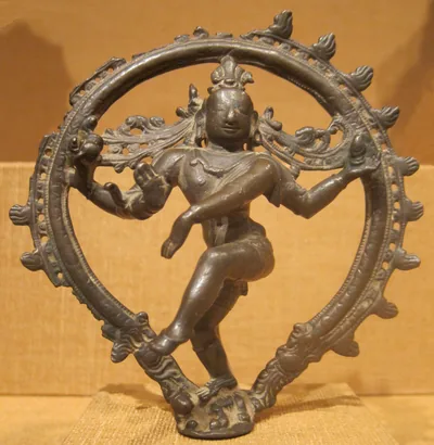 A bronze Nataraja on a warm gold background