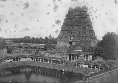 Old photo of a temple tower beside a large stepped tank