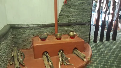 A traditional clay hearth with firewood and small pots on top