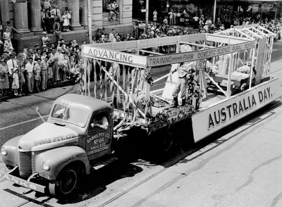 Black and white photo of a decorated float on a truck in a street parade
