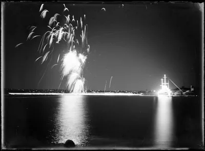 Black and white photo of fireworks reflected in the water of a harbour