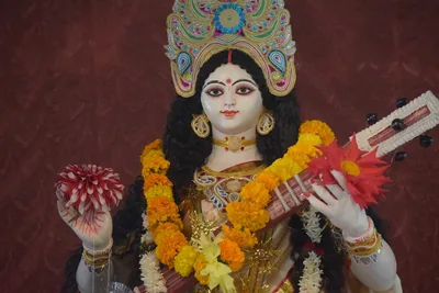 An idol of Goddess Saraswati with a veena, decorated with marigold garlands