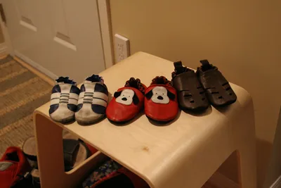 Rows of tiny baby shoes on a wooden shelf