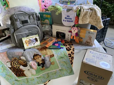 A table piled with baby gifts: soft toys, a blanket, a bag and boxes