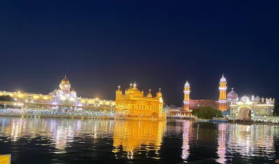 The Golden Temple glowing gold at night with its reflection in the sacred pool