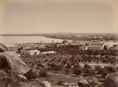 Old photo of a city spread beside a wide lake under a pale sky