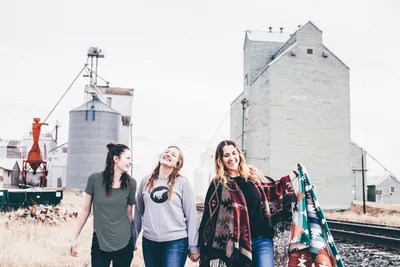 Three friends laughing beside railway tracks