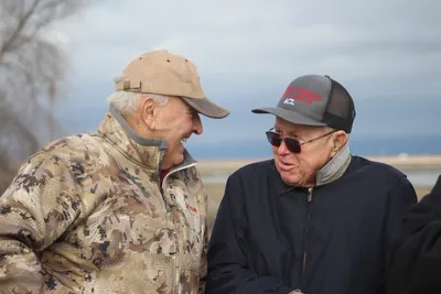 Two older men in caps laughing together outdoors