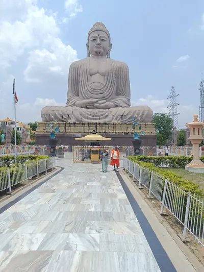 A huge seated stone Buddha at the end of a long marble path under a blue sky