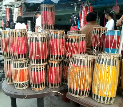 Rows of red and white painted dhol drums stacked at a market stall
