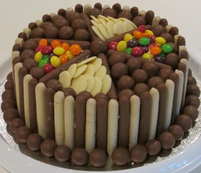 A chocolate cake ringed with wafer sticks and sweets