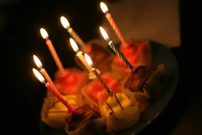 Cupcakes with tall lit candles in the dark