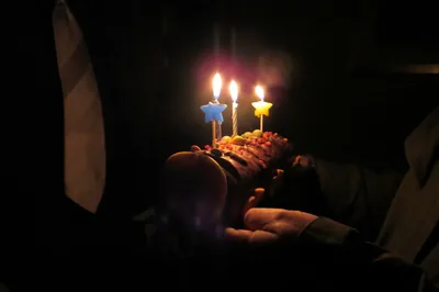 A small cake with star-shaped candles held up in the dark