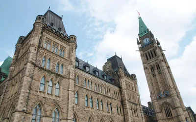 The stone Parliament buildings and Peace Tower under a blue sky