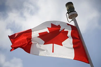 The red and white maple leaf flag flying against a cloudy sky