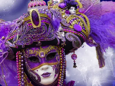 A purple and gold Venetian mask with jewels and a feathered hat