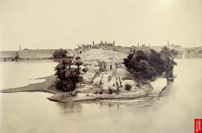 Old sepia photograph of an island with old buildings and trees in the middle of a wide river