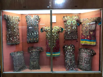 Colourful Sindhi embroidered dresses with mirror work displayed in a museum case