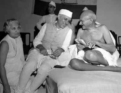 Black and white photo of Nehru and Gandhi sitting together and laughing