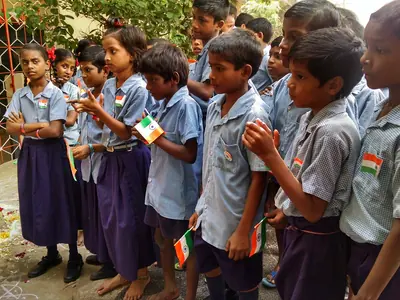 A group of schoolchildren in blue uniforms holding small Indian flags