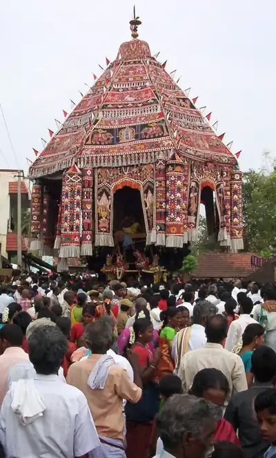 A tall temple chariot covered in red and white cloth, pulled through the street at a car festival in Tamil Nadu