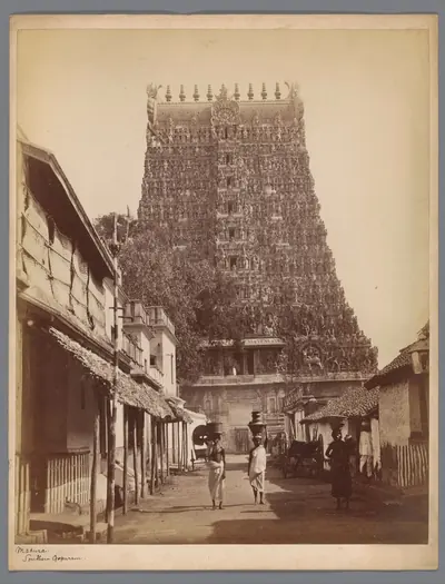 Old photo of a carved temple tower above a street with people