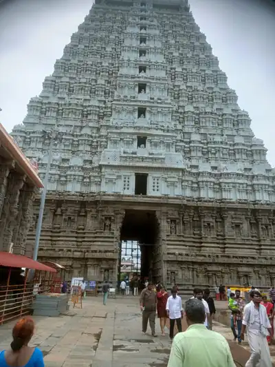 A huge temple tower over a stone courtyard with visitors walking in