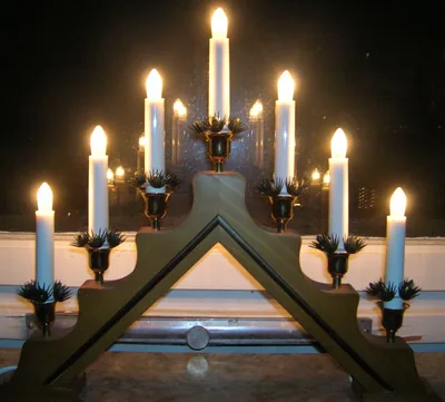 A wooden candle arch with glowing candles in a dark window