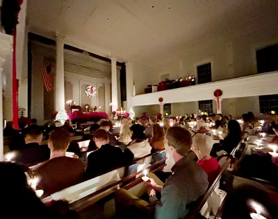People sit in church pews holding candles during an evening service