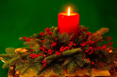A red candle among pine and red berries