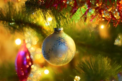 A glass bauble on a Christmas tree with warm lights