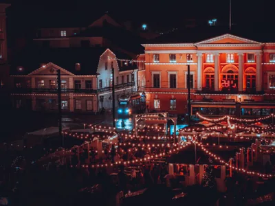 A town square at night strung with warm Christmas lights over market stalls