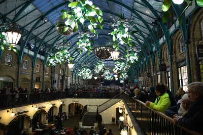 Lanterns and green mistletoe balls hang under the glass roof of a covered market