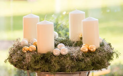 Four white candles on an advent wreath with gold baubles