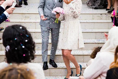 A bride and groom walking down steps under falling petals