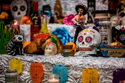 An ofrenda with sugar skulls, pan de muerto, candles and paper decorations