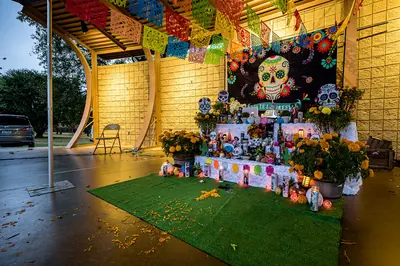 A large altar decorated with marigolds, papel picado and a painted skull