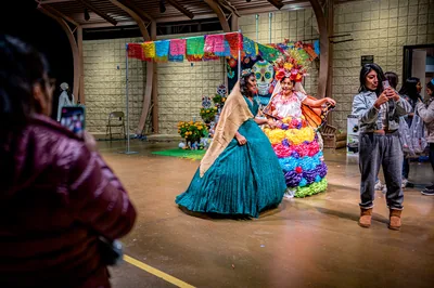 Dancers in flowing dresses and flower costumes performing in a hall