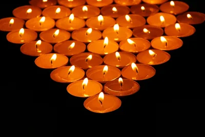 Rows of small candles arranged in a pointed shape, all glowing