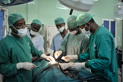 A team of surgeons in green gowns at work in an operating room