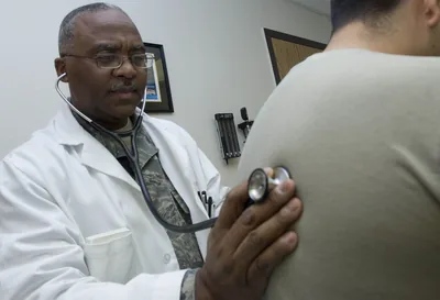 A doctor in a white coat listening with a stethoscope