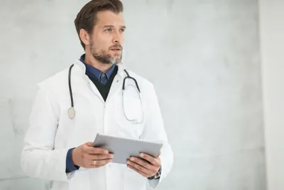 A doctor in a white coat holding a tablet