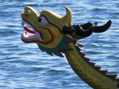 A carved green and yellow dragon head on the bow of a boat